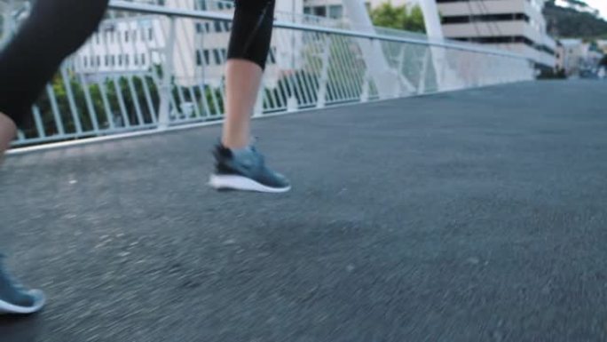健身女性的脚穿着跑鞋，在城市的一座桥上快速跑上楼梯，同时进行有氧运动训练。运动的女性活跃并锻炼以保持