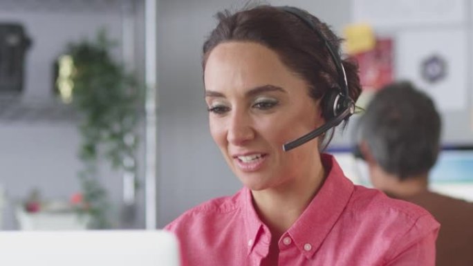 女商人戴着电话耳机在客户服务呼叫中心与客户交谈