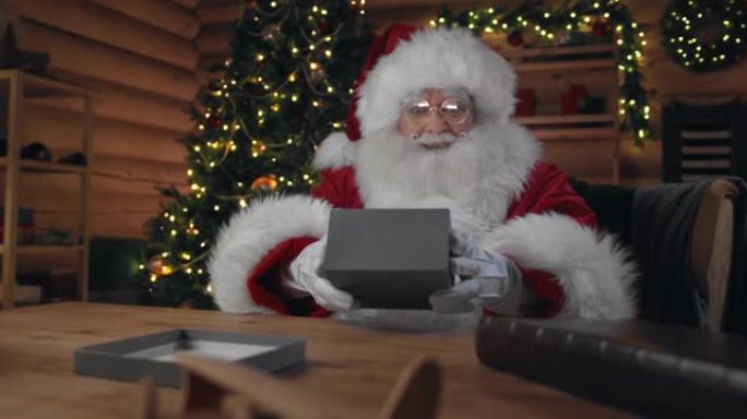 惊讶的圣诞老人打开了一个灰色的礼品盒，里面有光线，然后关闭了他所看到的礼物