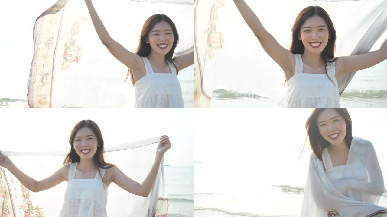 日本女子飘动围巾在日落时在海滩上旋转