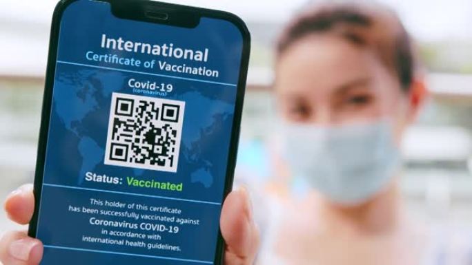 特写亚洲女商人戴着防护口罩，在智能手机上展示数字电晕病毒疫苗护照