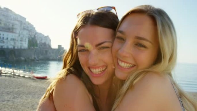 两个开朗的女人在海滩上亲切地拥抱在一起。快乐的年轻朋友在海滩上深情
