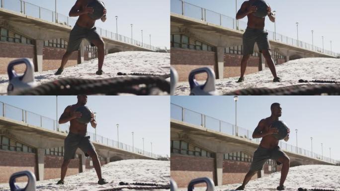 专注的非洲裔美国人举起球，在海滩上户外锻炼