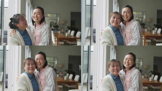 快乐的亚洲母亲和成年女儿在餐厅拥抱和微笑的肖像