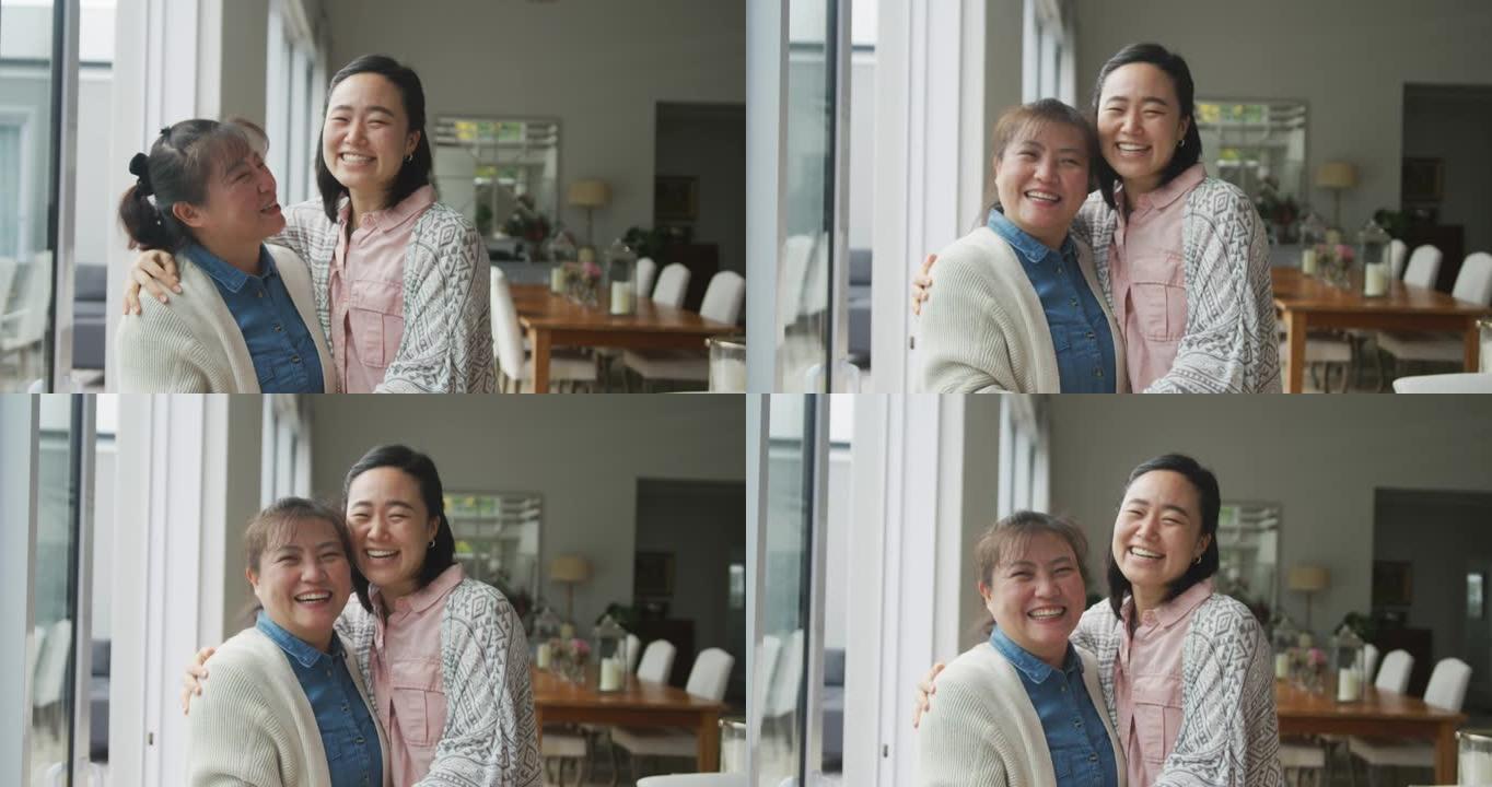 快乐的亚洲母亲和成年女儿在餐厅拥抱和微笑的肖像