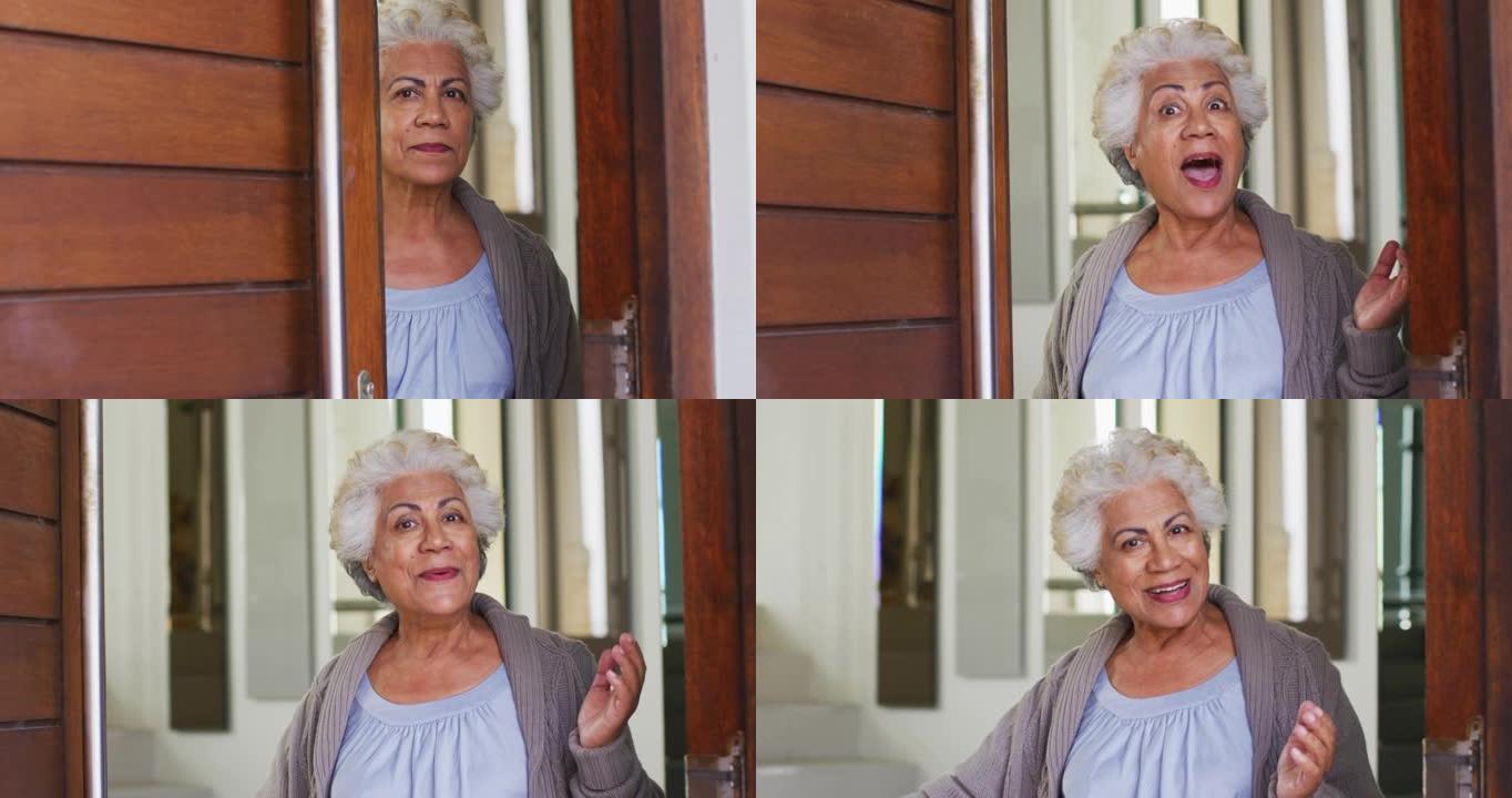 非裔美国高级妇女打开前门并在家中欢迎的肖像
