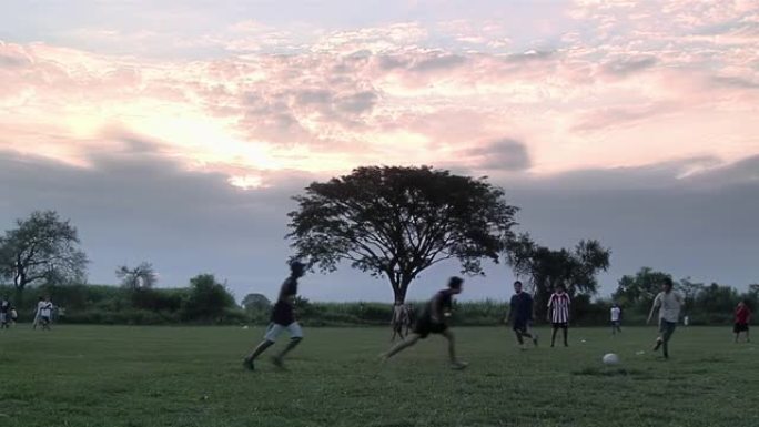 一群年轻的男孩在日落时在阿根廷布宜诺斯艾利斯省的一个运动场上踢足球。