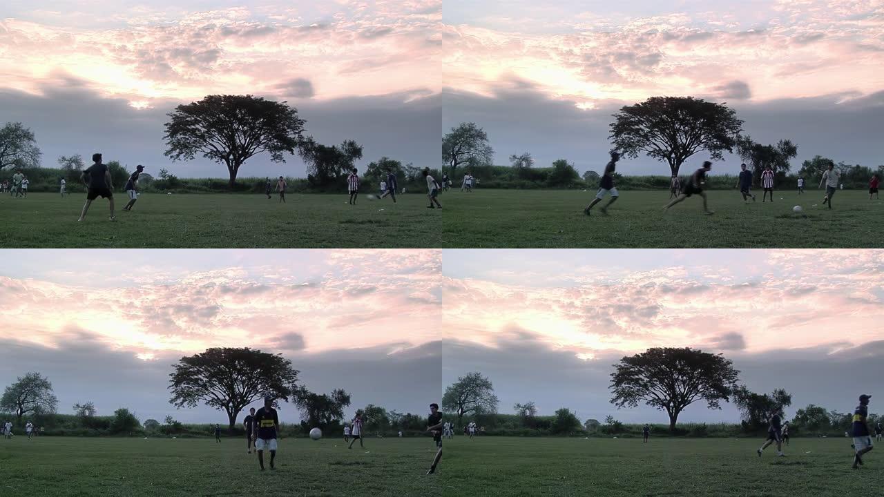 一群年轻的男孩在日落时在阿根廷布宜诺斯艾利斯省的一个运动场上踢足球。