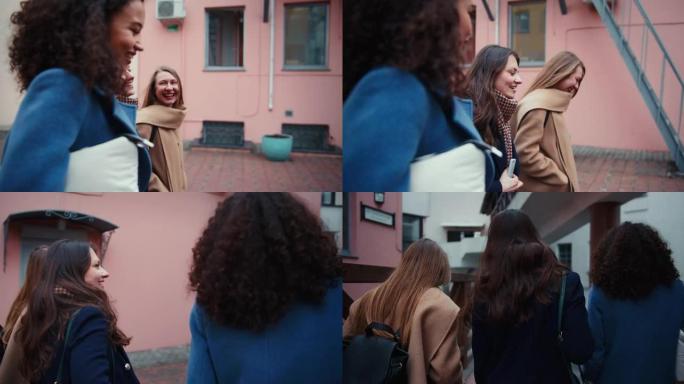 侧面和后视的快乐年轻女性朋友沿着老城区的街道随意聊天，女孩的力量概念。