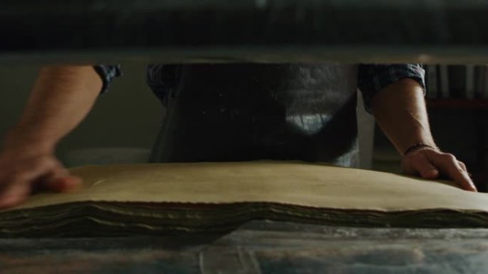 手工造纸大师的特写镜头正在触摸一张手工纸，以控制车间的质量。手工制作的概念，高品质，工匠，意大利制造