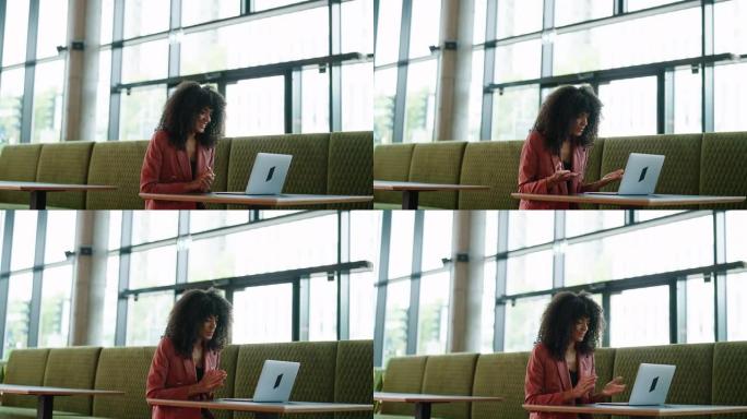 非洲妇女坐在餐厅里用笔记本电脑进行视频通话