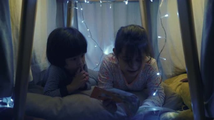 男孩和女孩晚上在自制帐篷里看书
