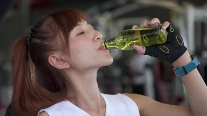 亚洲妇女在健身房喝矿泉水
