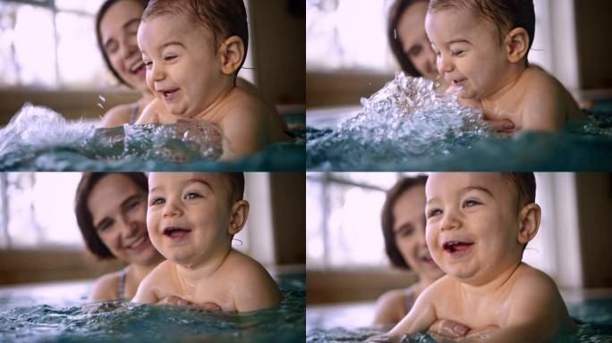 快乐的宝宝在室内游泳池里泼水和妈妈玩耍