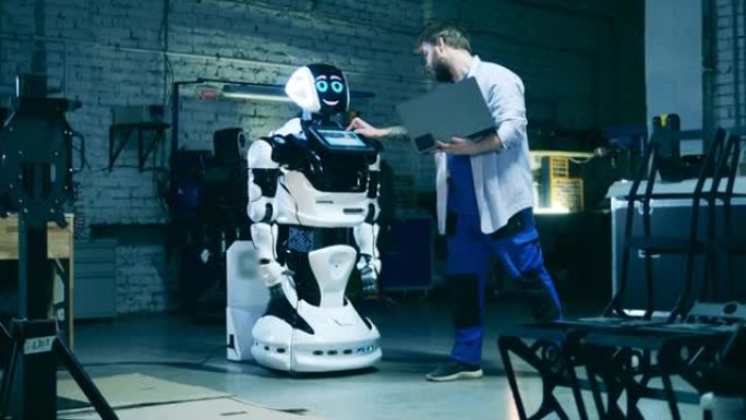 拿着笔记本电脑的服务员正在观察一个现代机器人。人与机器人交流概念。