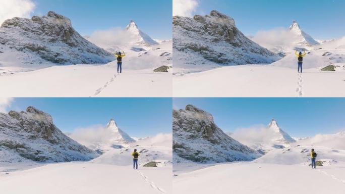 旅行者的空中无人机视图年轻女性在瑞士马特宏峰山顶上张开双臂向空中举起手臂。体验旅行与多样性。与阿尔法