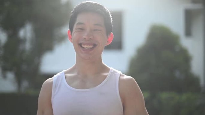爆头亚洲中国男运动员在日落时看着相机微笑
