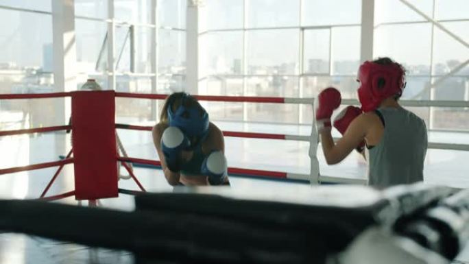 在健身房室内戴着安全帽和手套的活跃年轻女子拳击的慢动作
