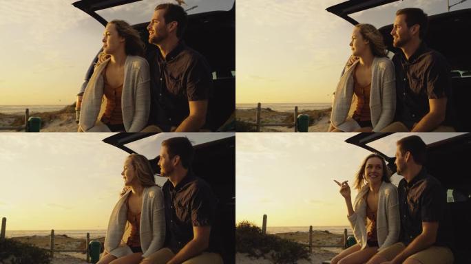 4k视频片段，一对夫妇坐在他们的车辆后部，同时在海滩上观看日落