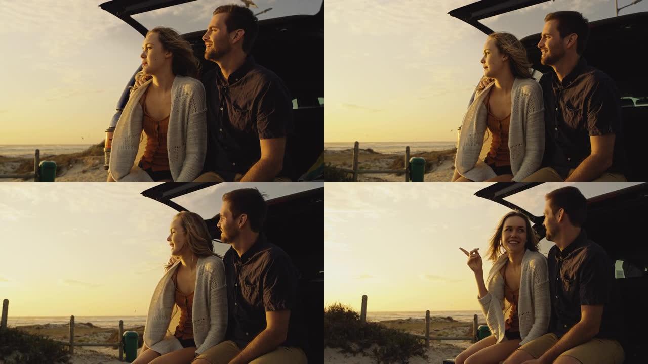 4k视频片段，一对夫妇坐在他们的车辆后部，同时在海滩上观看日落