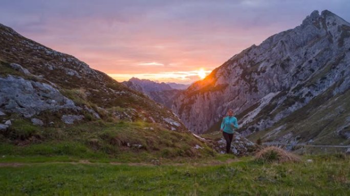运动活跃的女人在日落时在山区的岩石小径和草坡上慢跑