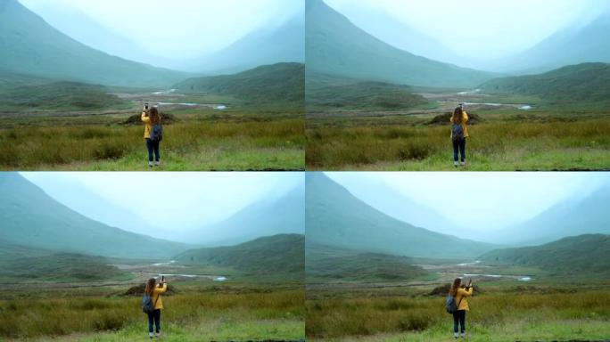 4k视频片段，一名妇女在远足时拍摄了一座山的照片