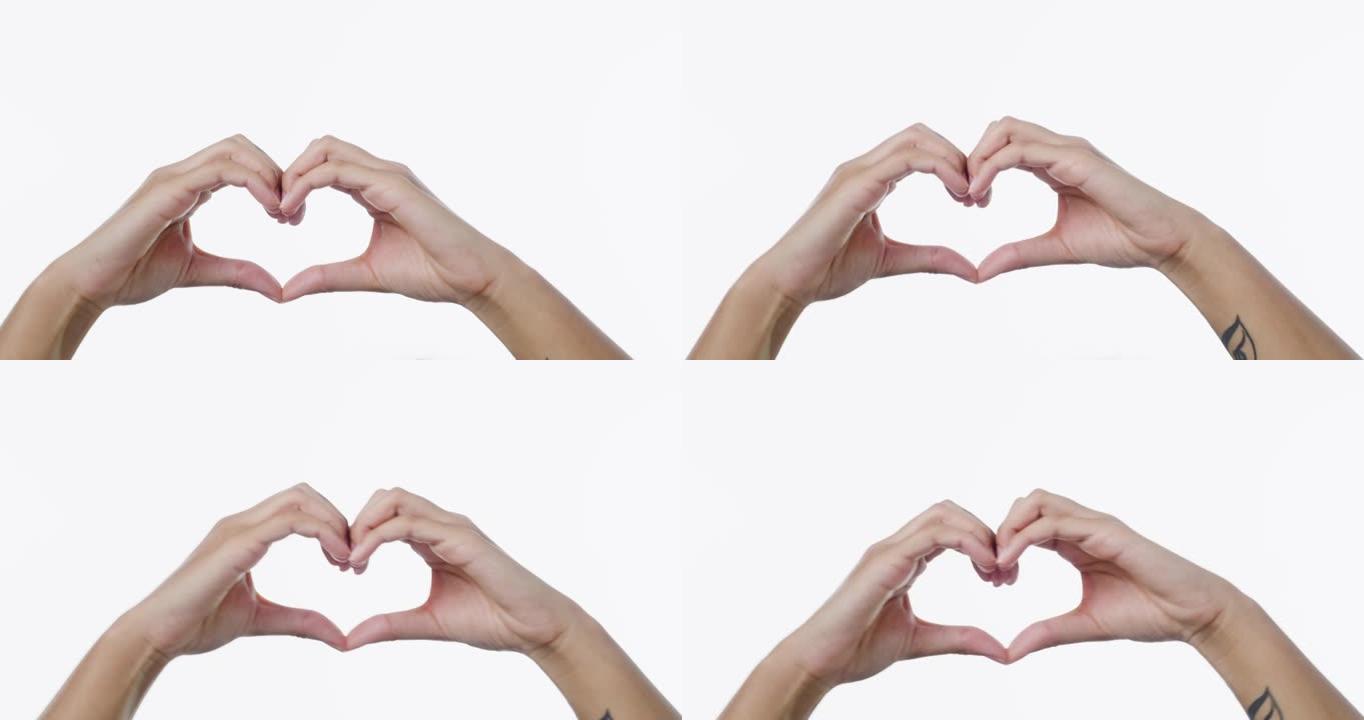 4k视频片段，一个无法识别的女人用手在白色背景下制作心形