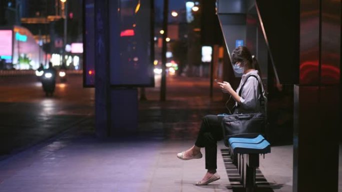 女人晚上在公交车站使用智能手机