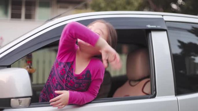 可爱的亚洲小女孩在汽车座椅后部挥手告别