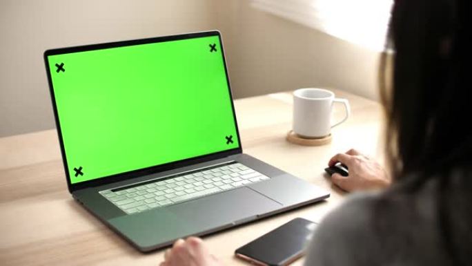 女人在家里的桌子上使用绿屏笔记本电脑
