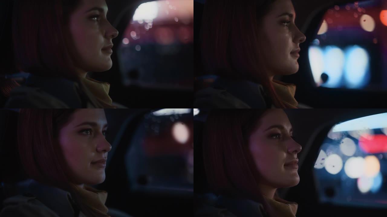 夜间在出租车后座上的女性通勤回家的特写肖像。美丽的女人乘客在城市街道上开着霓虹灯的汽车时看着窗外。电