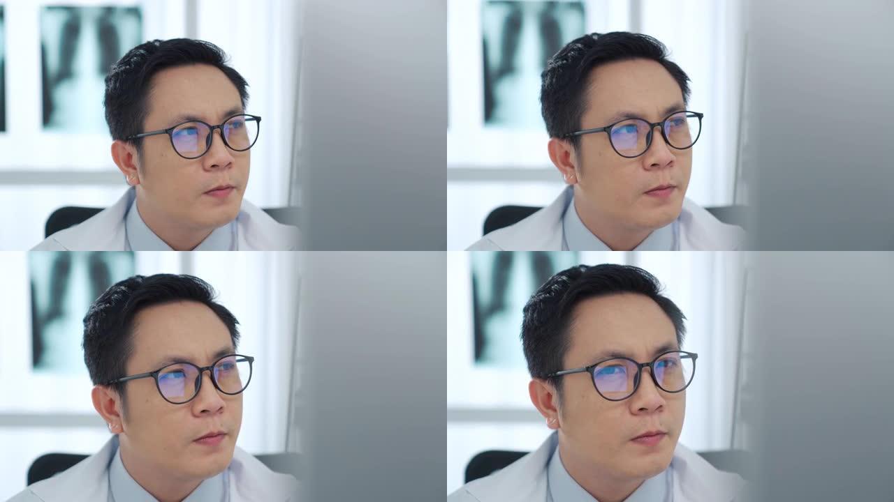 在医疗室戴眼镜并在计算机上工作的男医生的特写镜头