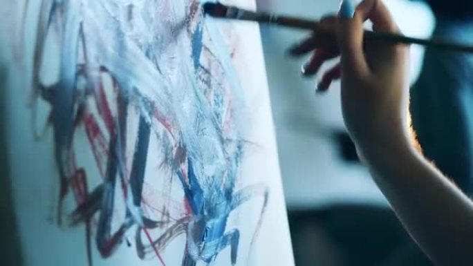 女性的手正在用画笔在画布上画画