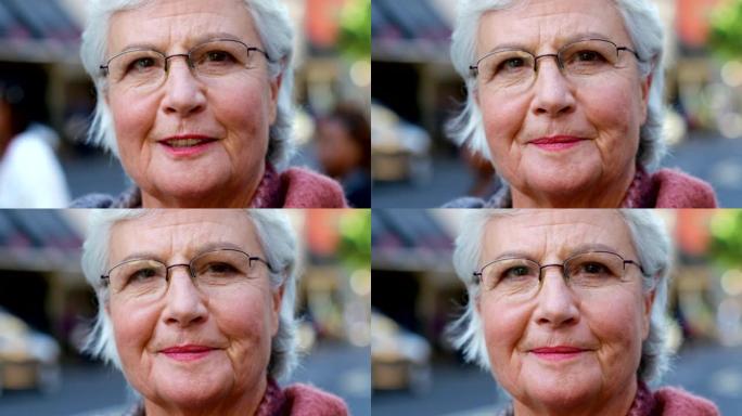 一位戴着眼镜，在城市外出时微笑的高级妇女的肖像。站在外面的一位满脸皱纹的老妇人的脸。养老金领取者旅行