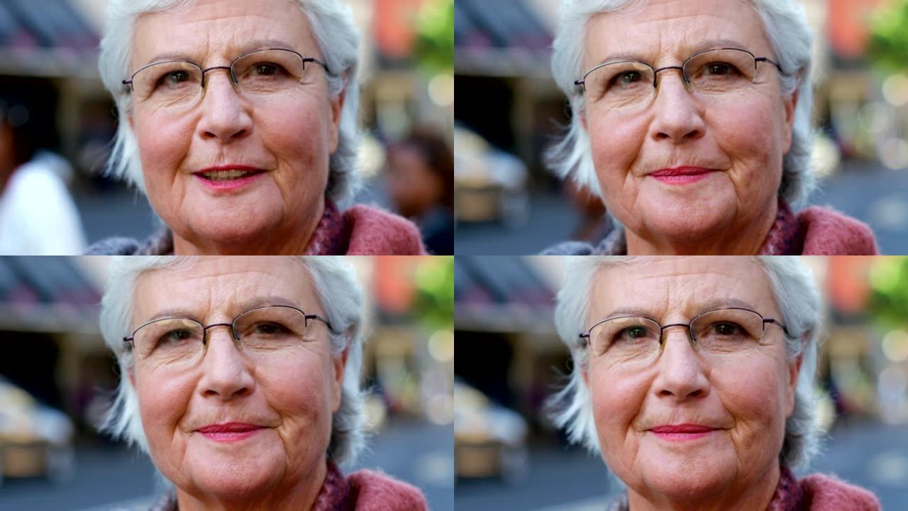 一位戴着眼镜，在城市外出时微笑的高级妇女的肖像。站在外面的一位满脸皱纹的老妇人的脸。养老金领取者旅行