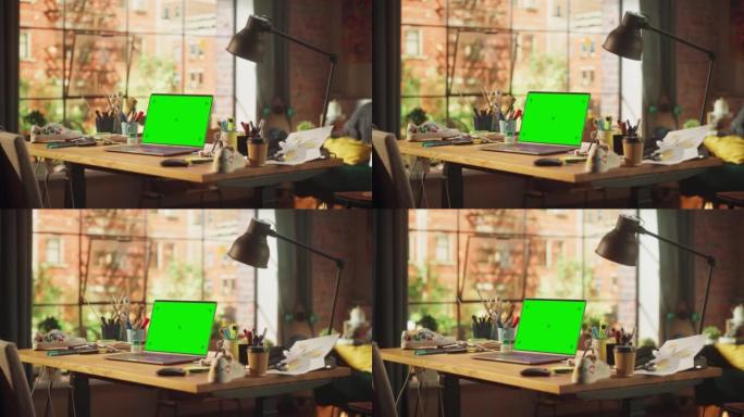 带有模拟绿屏色度键显示屏的笔记本电脑站在现代阁楼工作区的桌子上。在背景开放空间工作室与城市窗口视图。