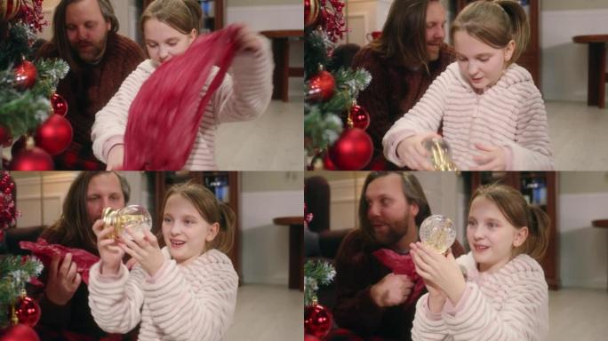 年轻女孩用神奇雪球打开圣诞礼物