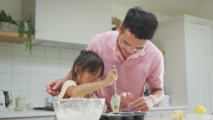 亚洲父女在家里一起在厨房里烤纸杯蛋糕
