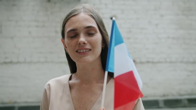 举着国旗微笑的快乐法国女孩的慢动作独自站在户外