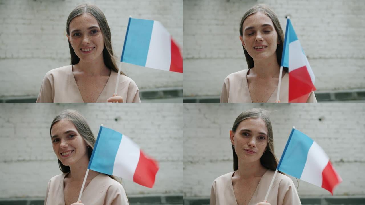 举着国旗微笑的快乐法国女孩的慢动作独自站在户外