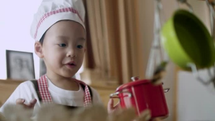 亚洲男孩在房子的厨房里扮演厨师的角色