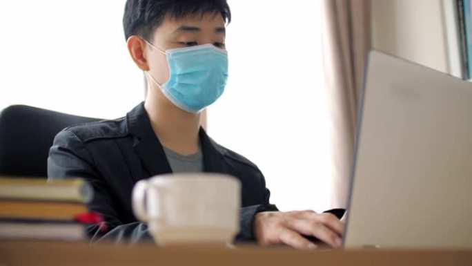 冠状病毒新型冠状病毒肺炎传播期间戴着口罩在家工作的年轻人