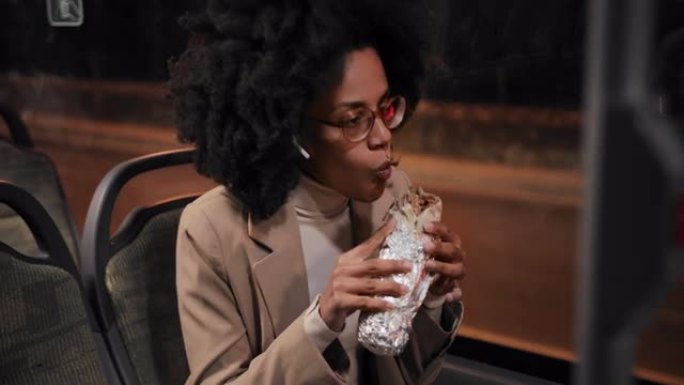 非裔美国女商人在公共巴士上吃不健康的食物