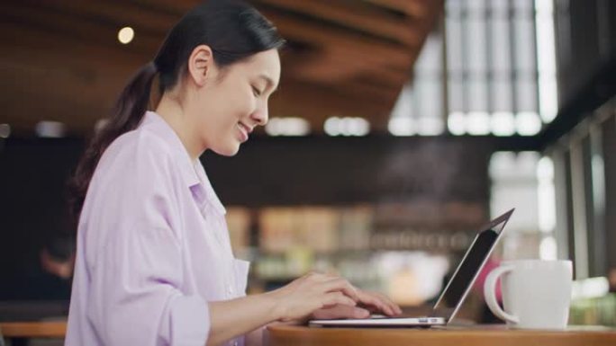 在咖啡馆使用笔记本电脑的亚洲妇女