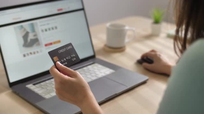 女人的手拿着信用卡在笔记本电脑上的在线网站商店购物在线付款