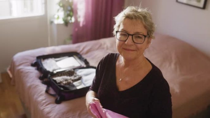 一位高级妇女打包行李箱的肖像
