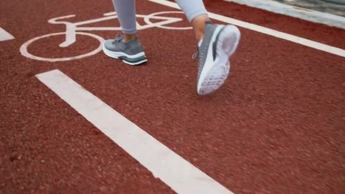一位女性跑步者的脚，穿着灰色运动鞋在自行车上行走