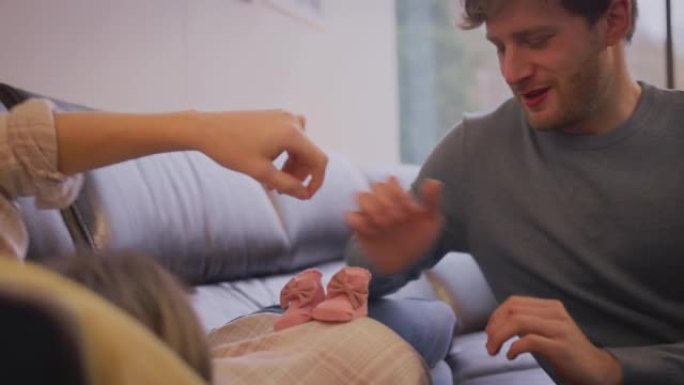 男子在家用假肢将婴儿鞋放在怀孕伴侣的肚子上-慢动作射击