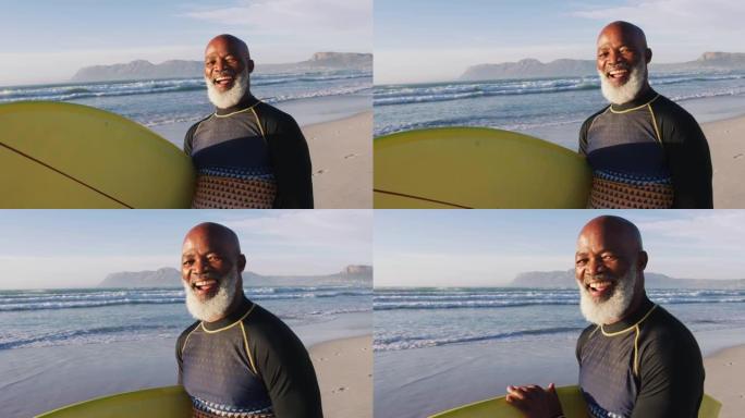 微笑的非裔美国高级男子在沙滩上与冲浪板同行