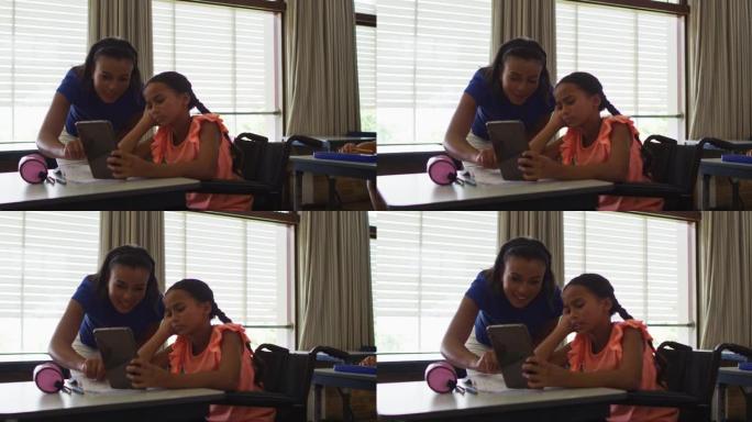 多元化的微笑女教师帮助坐在轮椅上的女学生使用平板电脑